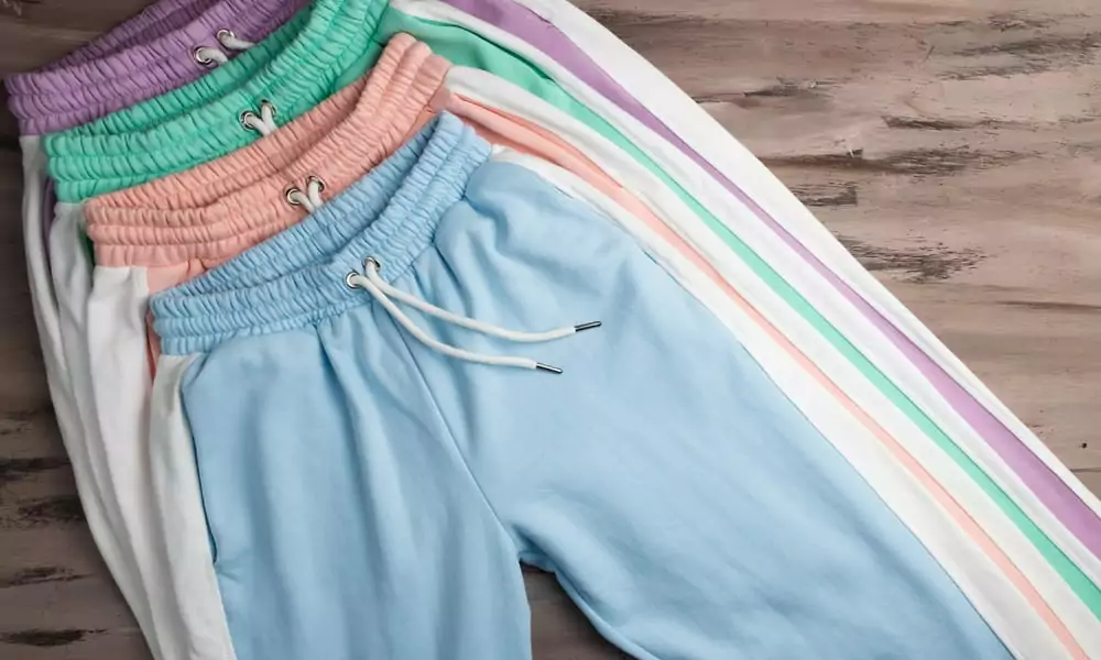 Ein Bild von einem Paar farbenfrohe Sport-Sweatpants, die auf einem Holzstück präsentiert werden. Das Motiv hat einen modischen Hintergrund.