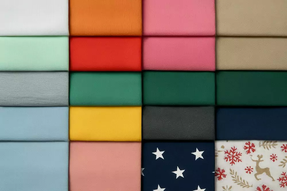 Farbfächer aus 16 verschiedenfarbigen Panama-Stoffen, geordnet in vier Reihen, mit Uni-Tönen wie Mint, Pink, Grau, Blau, Gelb, Dunkelgrün, Navy und Mustern wie Sternen und Rentieren – zeigt die große Auswahl an Dekostoffen