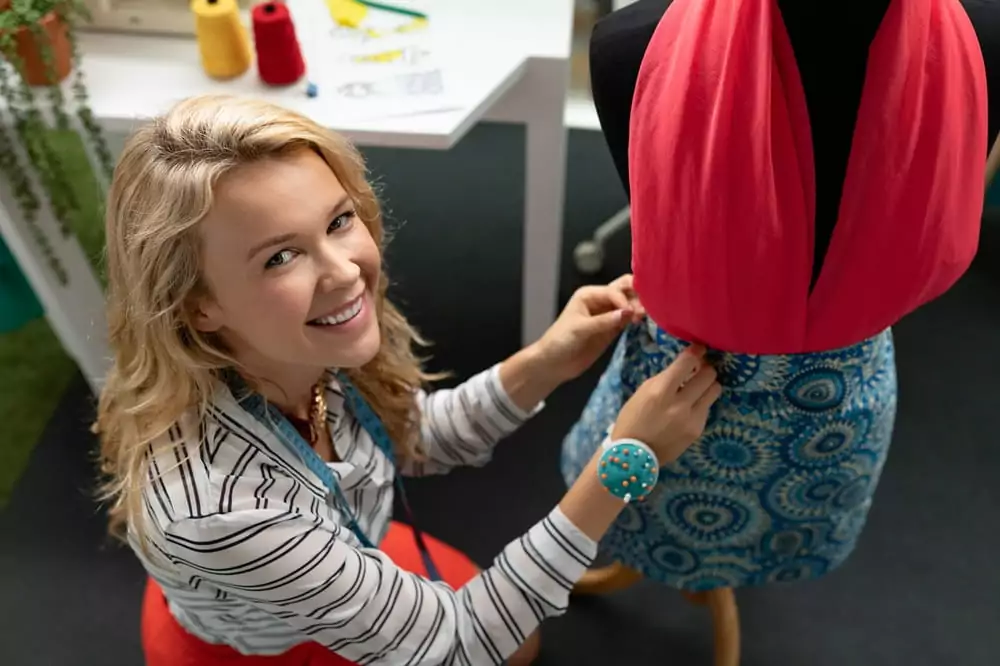 Modedesignerin kleidet eine Schaufensterpuppe in ihrem Designstudio ein.