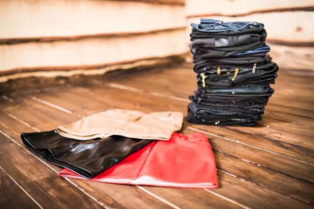 Wunderschöne bunte Miniröcke liegen auf einem Haufen dunkler Kleidungsstücke, der auf einem Holzboden liegt.