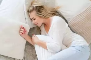 Eine junge blonde Frau schläft friedlich im Bett und umarmt ihr Kissen.