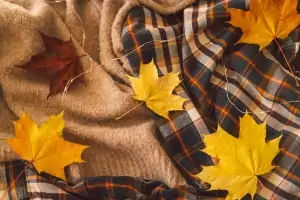 Hintergrund mit warmen Pullovern, Strickkleidung und gelben Herbstblättern, warmer Hintergrund