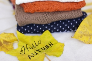 Ein Stapel warmer Pullover und ein gelbes Ahornblatt