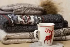 Stapel Winterkleidung und eine Tasse